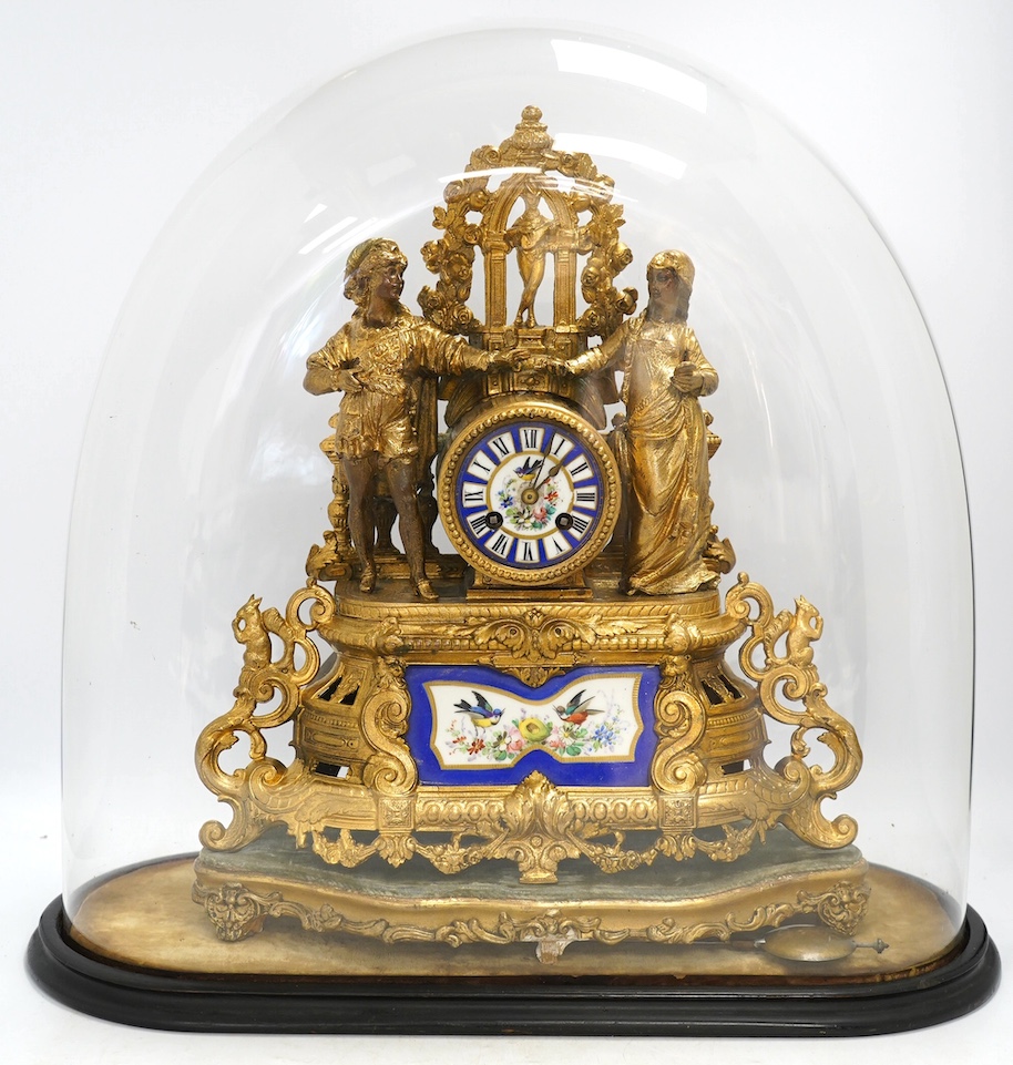 A large gilt metal figural mantel clock with floral porcelain dial and panels, under a glass dome, 52cm high (including stand). Condition - fair, not tested as working